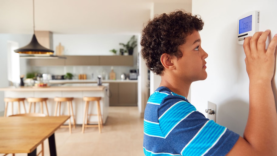 Boy changes temperature on thermostat